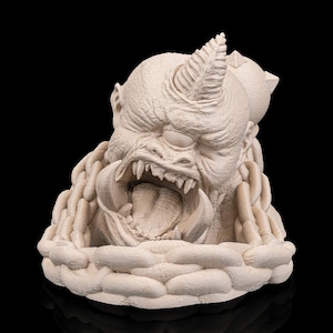 Può includere: Scultura beige di un mostro ringhiante con un corno e grandi denti. Il mostro è circondato da una struttura a catena e poggia su una base strutturata, il tutto su sfondo nero. Scultura molto dettagliata.