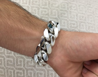 May include: A silver curb chain bracelet with large, flat links.