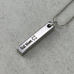 Puede incluir: Un collar de plata con un colgante de barra que dice "Rat Mom" con un pequeño icono de rata.