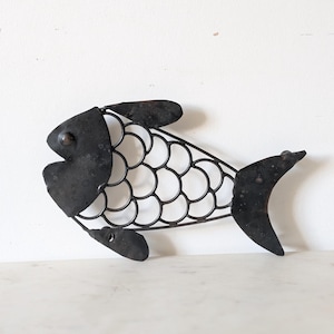Könnte beinhalten: Eine Wanddekoration in Fischform aus dunkelgrauem Metall mit einem massiven Kopf, einer Schwanzflosse und einer Flosse. Der Körper besteht aus einer Reihe miteinander verbundener Drahtschlaufen, die ein schuppenartiges Muster bilden.