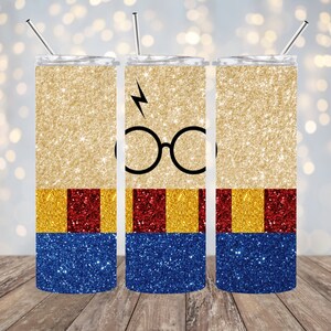 May include: Glittery tumbler with a design featuring a lightning bolt, round glasses, and color blocks of gold, red, and blue. The tumbler has a silver straw and lid. The design is reminiscent of a popular book series.