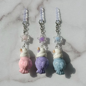 May include: Three phone charms featuring a cartoon bird with a white fluffy hat. The birds are pink, purple, and blue. Each charm has a silver chain with a clear star charm.