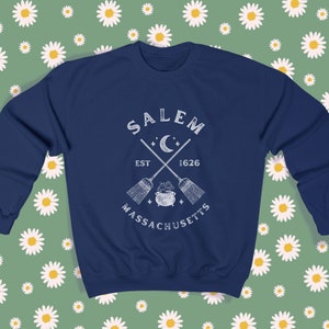 May include: A navy blue sweatshirt with a white graphic design featuring the text "SALEM EST 1626 MASSACHUSETTS" with a crescent moon and crossed broomsticks.