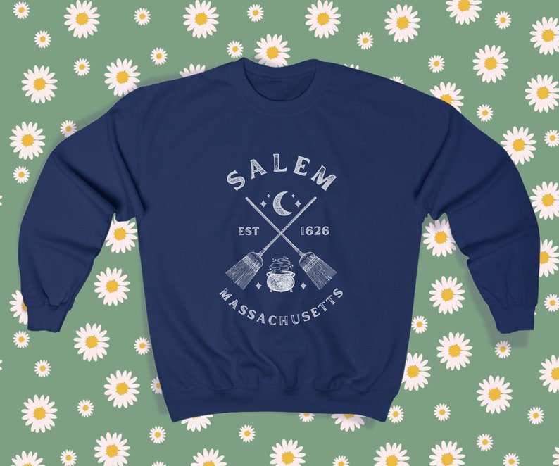 May include: A navy blue sweatshirt with a white graphic design featuring the text "SALEM EST 1626 MASSACHUSETTS" with a crescent moon and crossed broomsticks.