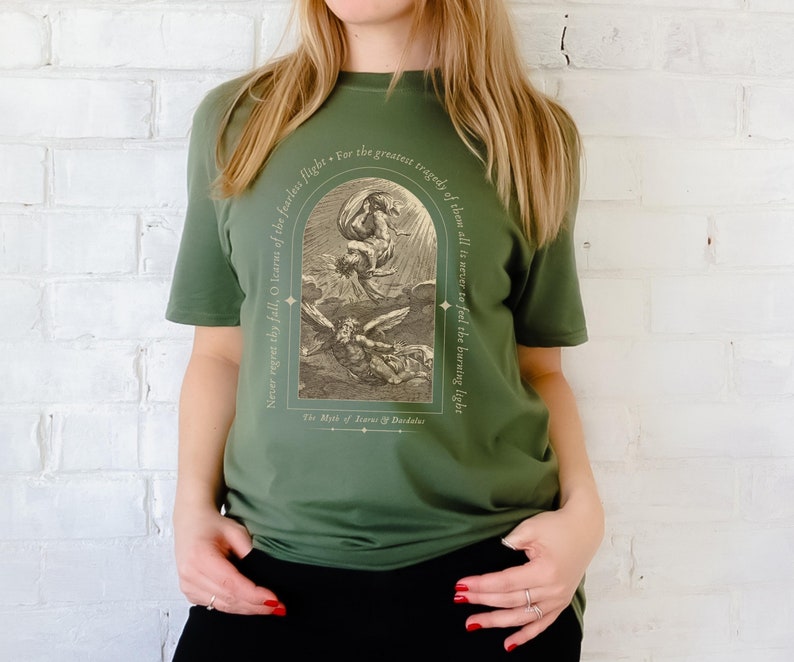May include: Green t-shirt with a vintage illustration of Icarus falling from the sky. The text reads "Never regret thy fall, O Icarus of the fearless flight. For the greatest tragedy of them all is never to feel the burning light. The Myth of Icarus & Daedalus."