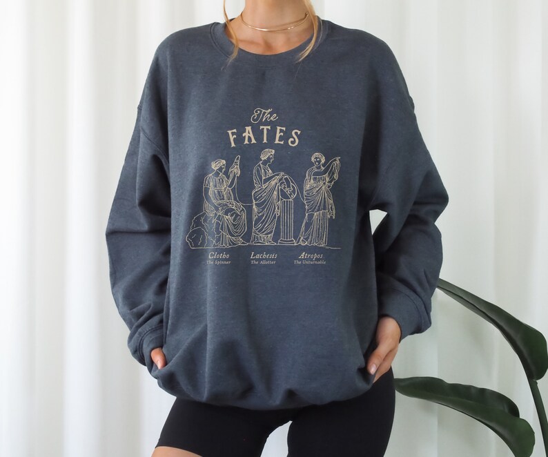 May include: A dark blue sweatshirt with a graphic of the three Fates, Clotho, Lachesis, and Atropos, from Greek mythology. The text "The Fates" is printed above the graphic.