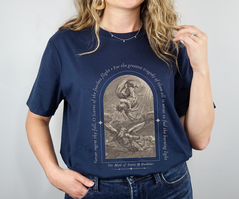 May include: A navy blue t-shirt with a vintage illustration of Icarus and Daedalus. The text reads "Never regret thy fall, O Icarus of the fearless flight. For the greatest tragedy of them all is never to feel the burning light. The Myth of Icarus & Daedalus."