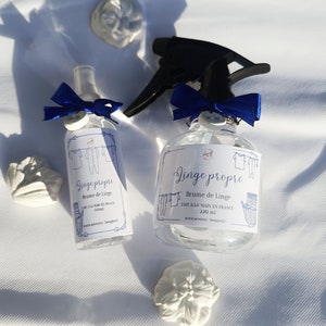 May include: Two clear glass spray bottles with blue ribbon bows and labels that read "Linge propre" in French. The labels also say "Brume de Linge" and "Fait a la main en France".