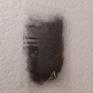 May include: A small package of dark brown human hair extensions.