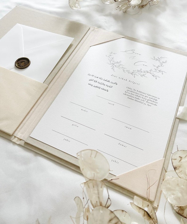 K&ouml;nnte beinhalten: Ein wei&szlig;er Ordner mit einem dekorativen Blumendesign auf der Vorderseite. Der Ordner ist ge&ouml;ffnet und zeigt ein leeres Formular mit dem Text "dini nikah belgeni" oben. Das Formular ist f&uuml;r eine Heiratsurkunde und enth&auml;lt Felder f&uuml;r den Namen des Br&auml;utigams, den Namen der Braut, das Datum und die Mitgift.