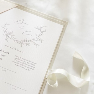 K&ouml;nnte beinhalten: Eine wei&szlig;e und beigefarbene Heiratsurkunde mit einem floralen Design und dem Text "Berna & Can dini nikah belgesi" in schwarzer Schrift. Der Text "Onlar, "Ey Rabbimiz! Eşlerimizi ve &ccedil;ocuklarımızı bize g&ouml;z aydınlığı kıl ve bizi Allah'a karşı gelmekten sakınanlara &ouml;nder eyle" diyenlerdir. Furkan Suresi(25) 74. Ayet" ist in Schwarz unter dem floralen Design gedruckt.