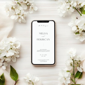 Könnte beinhalten: Ein weißes Smartphone mit einem schwarzen Bildschirm, auf dem eine Hochzeitseinladung für Melda und Bekircan angezeigt wird. Die Einladung enthält das Datum "03. 03. 2024" und den Ort "Class Palace Party Center, Calandstraat 100, 3013 BA Schiedam".