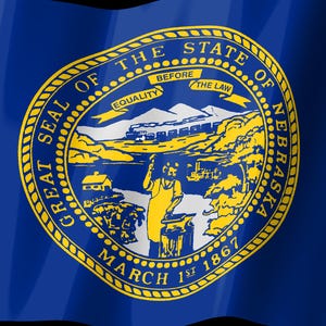 May include: The state flag of Nebraska features a deep blue field with the Great Seal of the State of Nebraska centered in gold. The seal depicts a blacksmith at an anvil, a train, mountains, and a banner reading EQUALITY BEFORE THE LAW.
