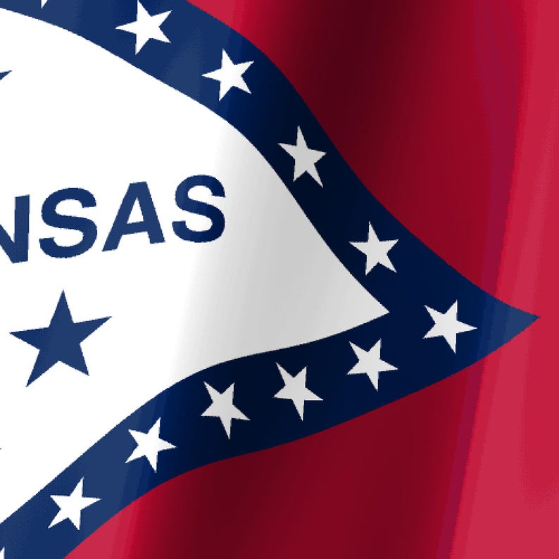May include: The state flag of Arkansas features a red field with a white diamond bordered in blue. Inside the white diamond, the text NSAS is visible in blue, accompanied by blue stars arranged in a circular pattern and a single blue star above.