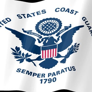 Op de afbeelding: Een witte vlag met het donkerblauwe embleem van de United States Coast Guard. Het ontwerp bevat een adelaar met een schild, de tekst UNITED STATES COAST GUARD, het motto SEMPER PARATUS, de Latijnse spreuk E PLURIBUS UNUM en het jaartal 1790.