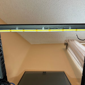 Op de afbeelding: Een close-up van een 3D-printer met een witte LED-lichtstrip die op het bovenste frame is ge&iuml;nstalleerd. De lichtstrip is bevestigd met kleine zelfklevende pads.