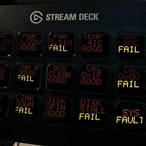 May include: A black Elgato Stream Deck control console featuring a grid of fifteen square LCD keys. The keys display various system status indicators in red and yellow text, including labels like PWR, TEMP, FAN, BUS, LINK, DISK, and SYS FAULT.