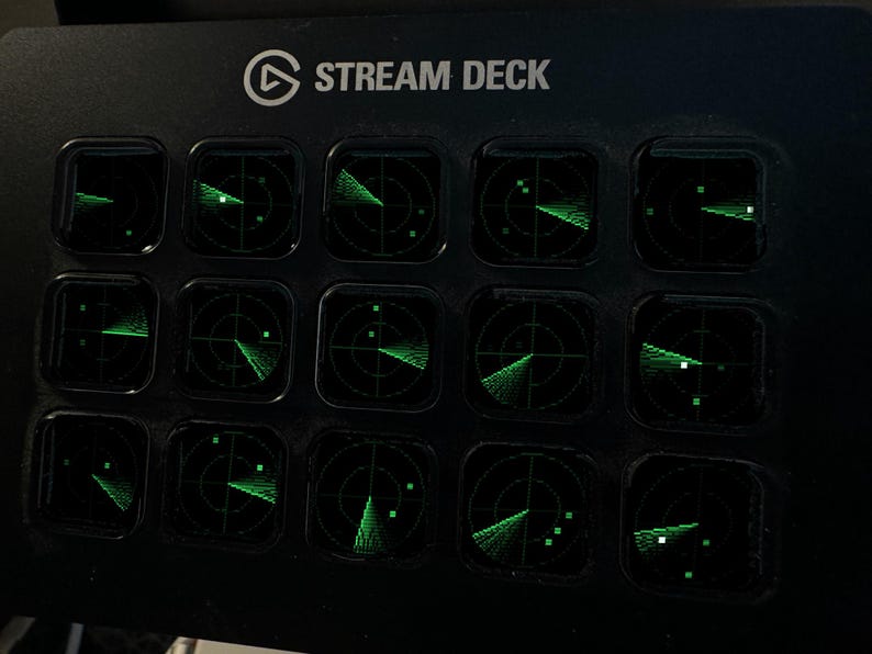 May include: A black Stream Deck control console featuring fifteen square keys arranged in a grid. Each key displays a glowing green radar screen graphic with circular grid lines and scanning beams, set against a dark background.
