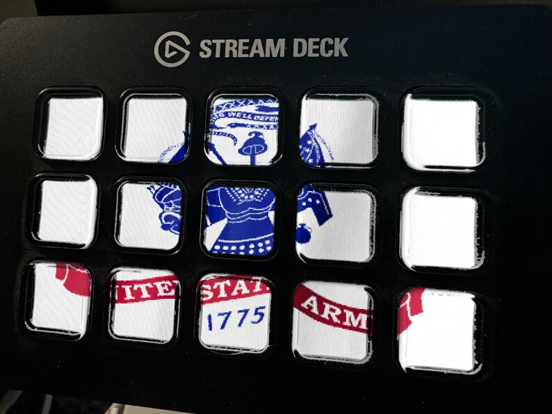 May include: A black Elgato Stream Deck controller featuring fifteen square LCD keys. The keys display a fragmented graphic of the United States Army seal, including the text 'UNITED STATES ARMY' and '1775' in blue and red on a white background.