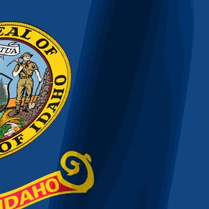 K&ouml;nnte beinhalten: Die Staatsflagge von Idaho zeigt ein tiefblaues Feld mit dem Staatssiegel auf der linken Seite. Das Siegel zeigt einen Bergarbeiter und eine Frau neben einem Fluss, Bergen und B&auml;umen. Unter dem Siegel befindet sich ein rotes Banner mit IDAHO in Gold.