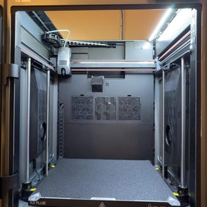 May include: A black 3D printer with a glass door, a white light inside, and a black build plate that says "CREALITY K2 PLUS 350 x 350 mm".