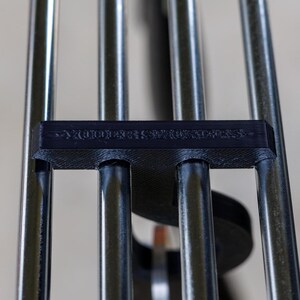 May include: Close-up of a wind chime with silver metal tubes and a black plastic piece with the text "YOU ARE SO LUCKY". The tubes are arranged vertically and connected to the black piece.