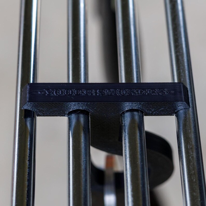 May include: Close-up of a wind chime with silver metal tubes and a black plastic piece with the text "YOU ARE SO LUCKY". The tubes are arranged vertically and connected to the black piece.