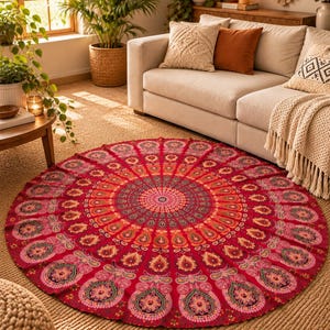 May include: A circular rug featuring a vibrant red base with a complex, symmetrical mandala pattern in shades of orange, yellow, pink, and dark purple. The design radiates from a central floral motif outward to repeating teardrop shapes.