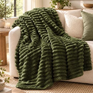May include: A dark olive green throw blanket with a textured, ribbed, and plush surface. The blanket features a series of raised, horizontal channels that create a consistent, repeating pattern across the entire fabric, draped over a sofa.
