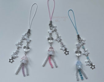 May include: Three phone charms with white pearl beads, silver stars, and clear heart-shaped beads. Each charm has a different colored flower-shaped bead at the bottom: pink, blue, and light blue.