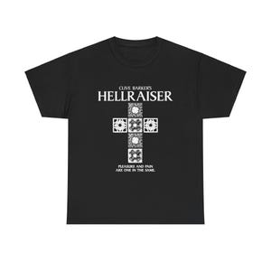 May include: Black t-shirt featuring the text "CLIVE BARKER'S HELLRAISER" in white, with a white cross-shaped graphic. The graphic includes intricate square designs. The phrase "PLEASURE AND PAIN ARE ONE IN THE SAME" is printed below.