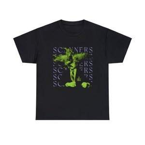 Puede incluir: Camiseta negra con un gráfico verde y morado de un hombre con una gran cabeza de cabello verde. El texto "SCANNERS" se repite en un patrón en la camiseta.