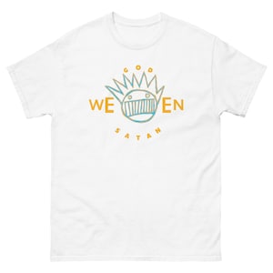 Puede incluir: Camiseta blanca con un gráfico de una cara de dibujos animados con una corona y las palabras "Dios" y "Satanás" arriba y abajo de la cara. Las palabras "Ween" están a cada lado de la cara.