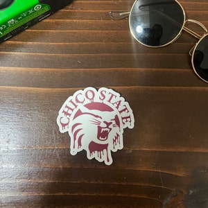 May include: A white sticker with a maroon outline and the words "Chico State" in a circular design. A maroon silhouette of a wildcat with a dripping effect is in the center of the sticker.