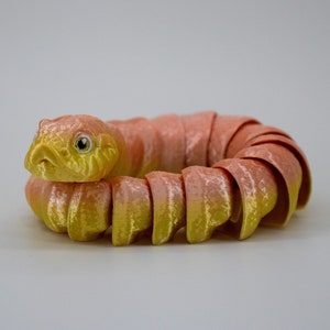 May include: A yellow and pink segmented snake toy, curled into a circle.