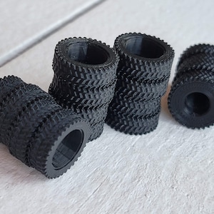 May include: A set of six black rubber tires with a tread pattern. The tires are stacked in groups of two and three.
