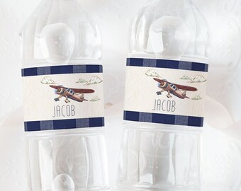 May include: Two clear plastic water bottles with blue and white patterned labels. The labels feature a cartoon airplane and the name "Jacob".