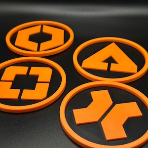 Könnte beinhalten: Vier orangefarbene und schwarze Untersetzer mit geometrischen Designs. Jeder Untersetzer hat eine schwarze Mitte mit einem orangefarbenen Rand und eine einzigartige orangefarbene Form in der Mitte. Die Formen umfassen ein Sechseck, ein Quadrat, ein Dreieck und zwei Pfeile.