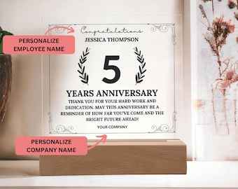 May include: A clear acrylic plaque with a black and white design celebrating a 5 year work anniversary. The plaque has the text "Congratulations Jessica Thompson 5 Years Anniversary Thank you for your hard work and dedication. May this anniversary be a reminder of how far you've come and the bright future ahead! Your Company".