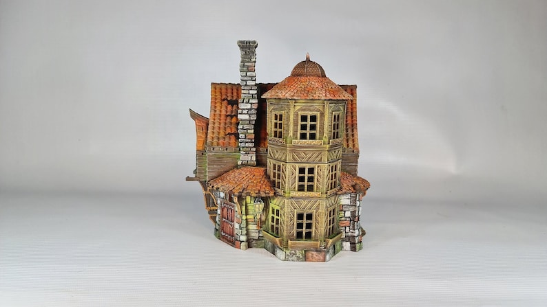 A painted miniature of a two-story fantasy building with a red-orange tiled roof, stone foundation, and wooden walls, viewed from the right side, showing a multi-level turret.