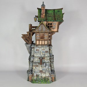 May include: A miniature model of a stone tower with a wooden house built on top. The house has a green roof and a small window. The tower has a stone wall with a small window and a door. The model is painted in realistic colors.