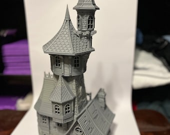 Può includere: Un modello 3D stampato in grigio di una torre con un tetto a punta e una torre più piccola in cima. La torre ha finestre e una porta. Il modello è su una superficie bianca.