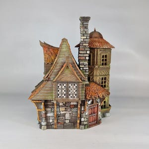 A painted miniature of a two-story fantasy building with a red-orange tiled roof, stone foundation, and wooden walls, viewed from the left side, showing a tall chimney.