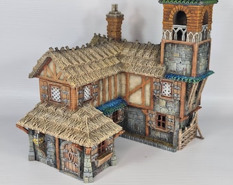 Può includere: Un modello in miniatura di un edificio con un tetto di paglia, muri in pietra e una torre con un tetto verde. L'edificio ha diverse finestre e una porta. Il modello è fatto di legno e plastica dipinti.