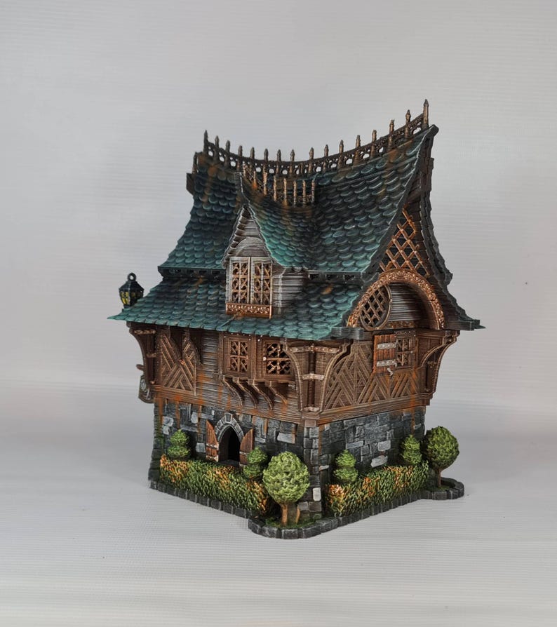 May include: A detailed miniature fantasy house with a green roof, wooden accents, and stone base. The house features intricate architectural details, including decorative trim, windows, and a small garden. The overall design evokes a whimsical, storybook aesthetic.