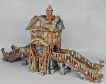Può includere: Un ponte in legno in miniatura con un piccolo edificio con tetto di paglia in cima. Il ponte ha una ringhiera in legno marrone e un arco in pietra. L'edificio ha un camino in pietra e una piccola finestra.