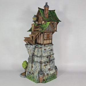 May include: A miniature model of a stone tower with a wooden house built on top. The house has a green roof and a small balcony. The tower is decorated with stonework and has a small tree growing at the base.