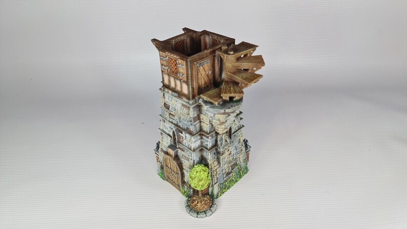 May include: A miniature stone tower with a wooden roof and a small wooden door. The tower has a wooden walkway and a small tree in front of it.