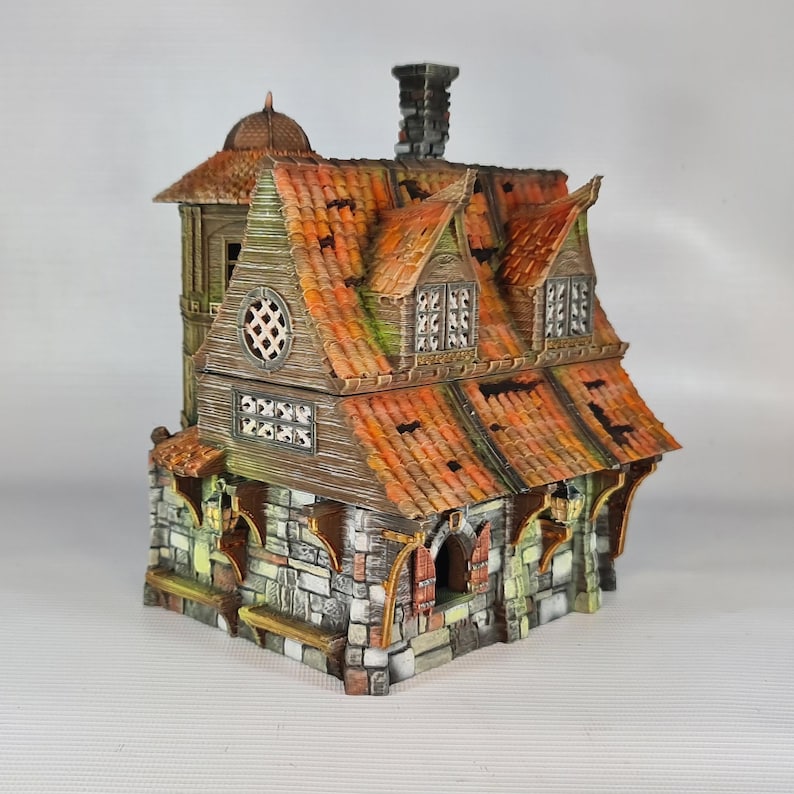 A painted miniature of a two-story fantasy building with a red-orange tiled roof, stone foundation, and wooden walls, viewed from the front-right.