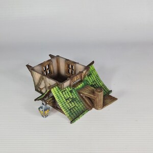 May include: A miniature wooden house with a green roof and two windows. The house has a small porch and a lantern hanging from the side.